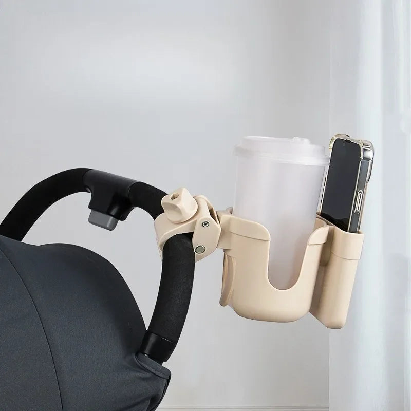 Beige cup holder attached to a stroller handle with a white cup and black phone inside.