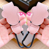 Pink cat-shaped hooks held by a person with a blurred background