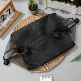 Black drawstring bag on a woven mat with a light gray background