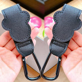 Black leather keychain carabiners held in hands with a blurred background