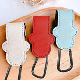 Three leather keychains in white, red, and light blue on a wooden surface.