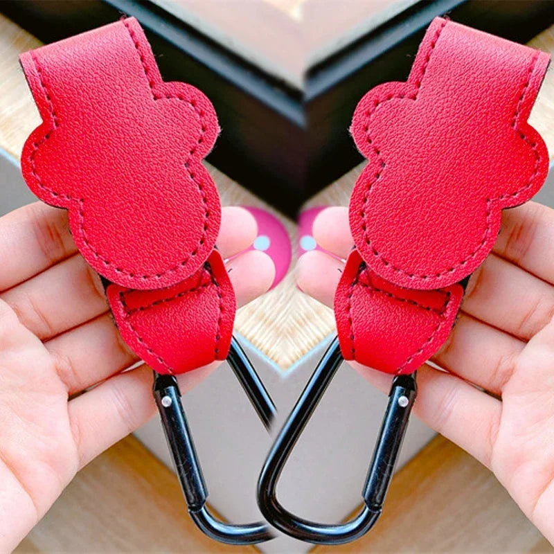 Red leather straps with black carabiners held by hands on a blurred background