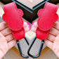 Red leather straps with black carabiners held by hands on a blurred background